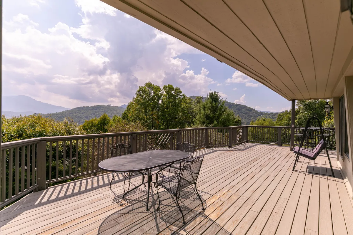 A spacious deck with a table and chairs set for outdoor dining, a hanging swing, and panoramic mountain views stretching into the distance. The setting is inviting and perfectly suited for relaxation or social gatherings, with the landscape showcasing the grandeur of the High Country.