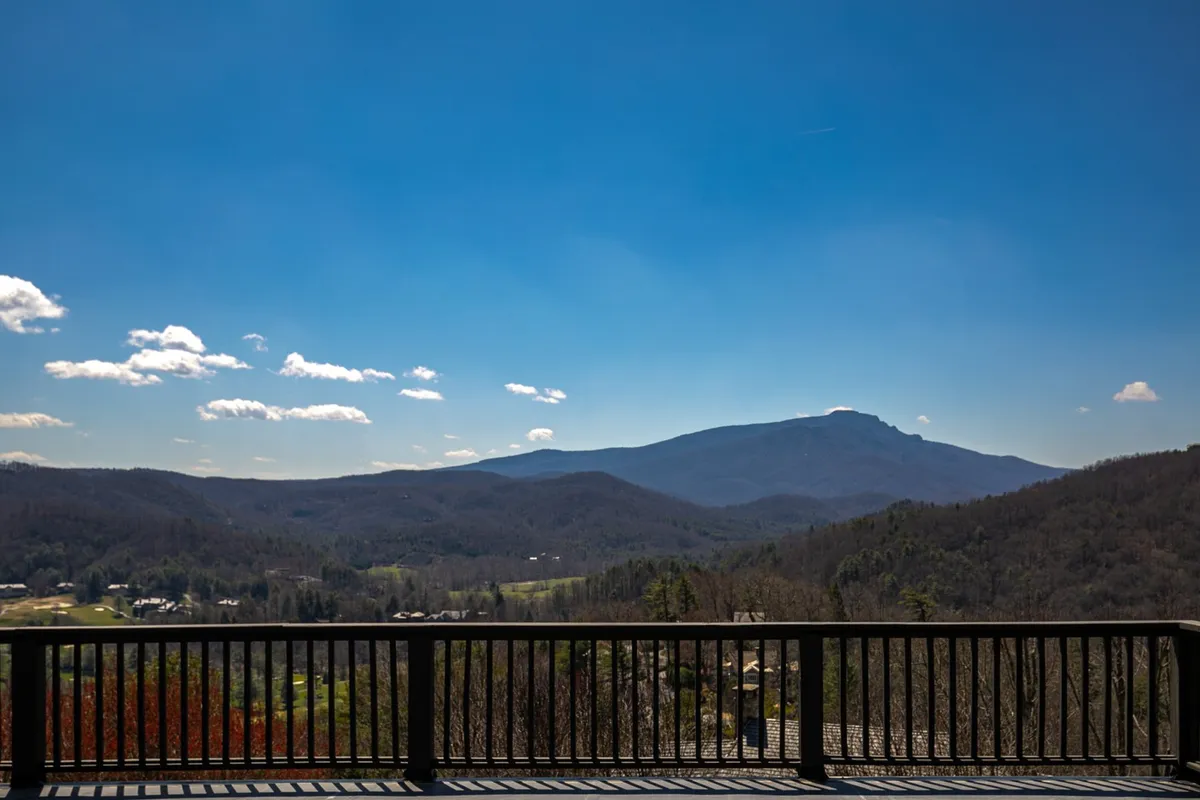 A panoramic mountain view unfolds under a vibrant blue sky, with lush green valleys stretching to the horizon. The scene evokes possibilities for hiking, nature photography, and experiencing the changing seasons firsthand.