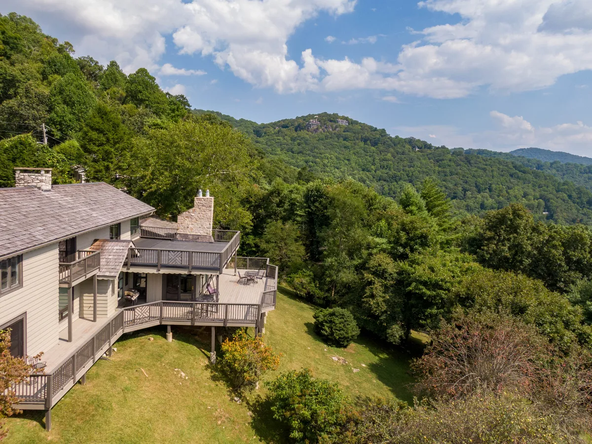 This image captures the exterior of Hawthorn House with a sweeping view of the house, its inviting deck, and the rolling mountain landscape beyond. The scene highlights the seamless integration between the home and its natural surroundings, suggesting immediate access to outdoor activities and the beauty of every season.