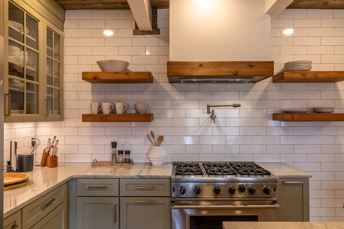 This image showcases a modern kitchen featuring a stainless steel gas stove, open wooden shelves, marble countertops, and glass cabinets. The space is bright and inviting, offering a clear view of high-end appliances and an organized layout.